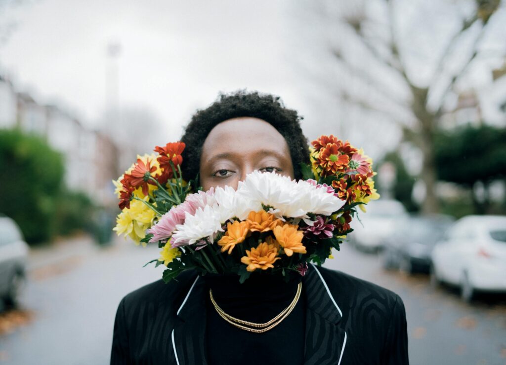 Creative portrait of a man with floral arrangement outdoors, blending art and nature.